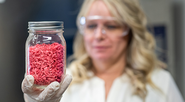 Researcher holds a jar full of bulk solids materials.
